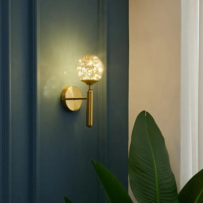 Postmodern gold glass globe wall light fixture with spherical crackled glass globe emitting warm light for bedroom use