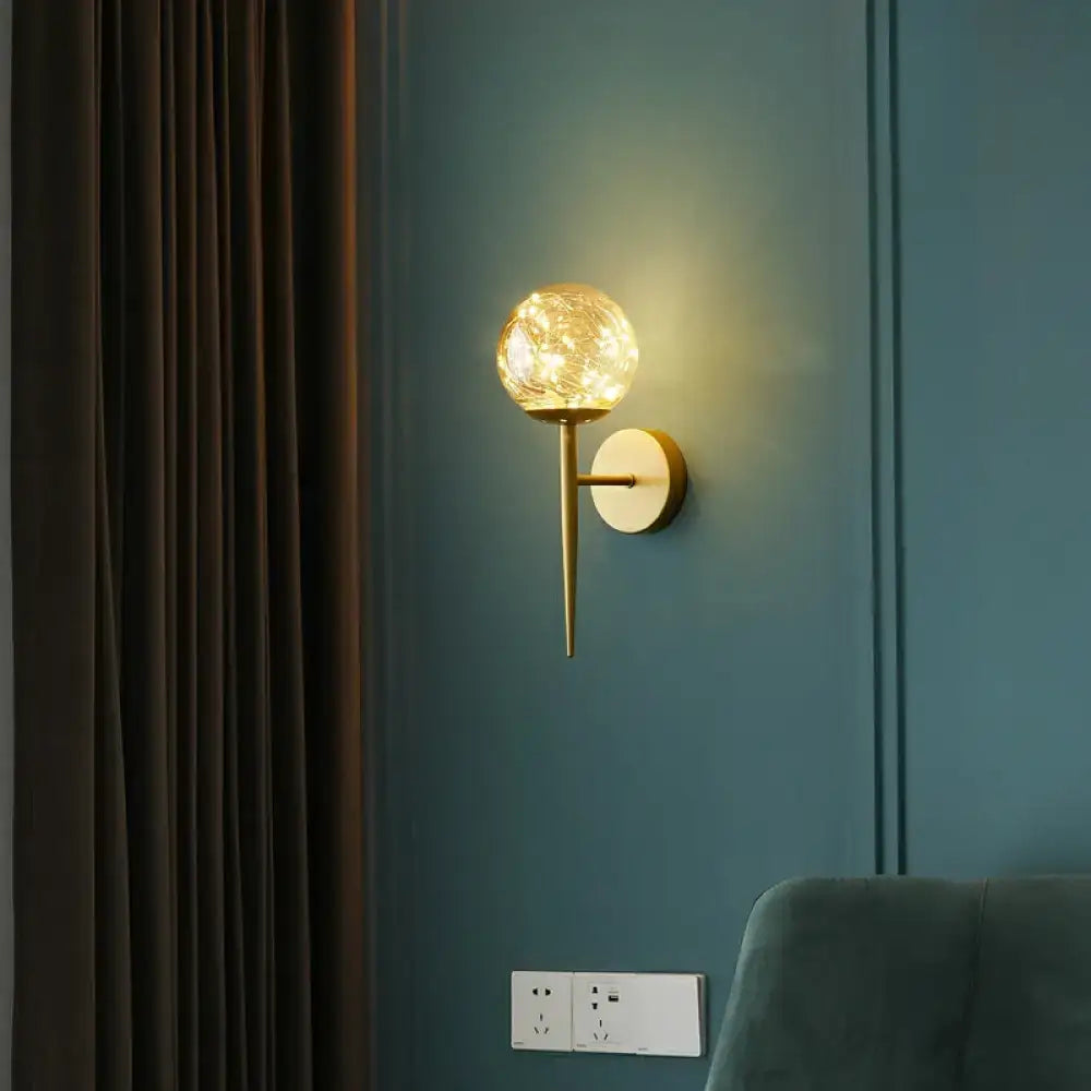 Postmodern gold glass globe wall light fixture with textured glowing globe and sleek metallic stem for bedroom use
