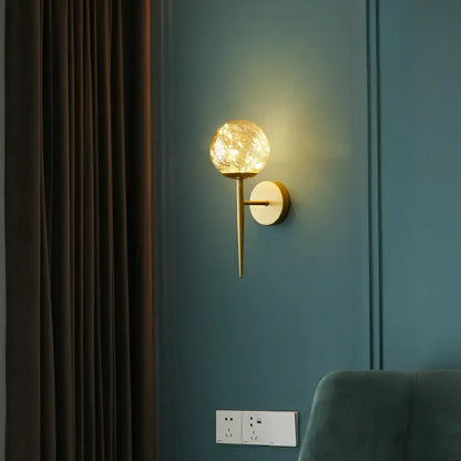 Postmodern gold glass globe wall light fixture with textured glowing globe and sleek metallic stem for bedroom use