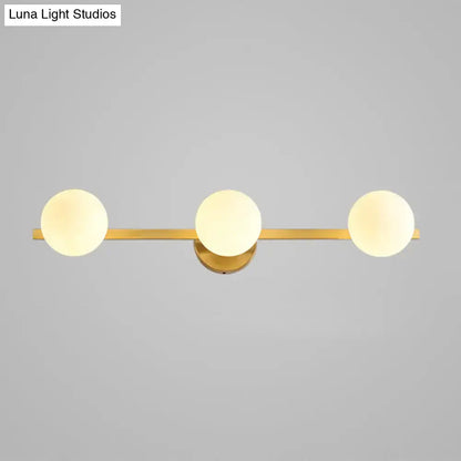Postmodern gold-toned wall sconce with three frosted glass globe shades and 11in fixture height for bathroom use
