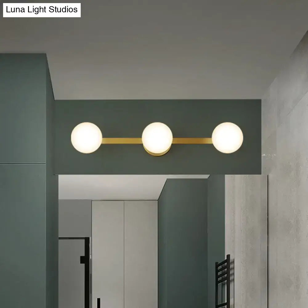 Modern three-light vanity fixture with frosted glass globe bulbs and gold-toned bulb base with fixture height 11in