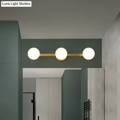 Modern three-light vanity fixture with frosted glass globe bulbs and gold-toned bulb base with fixture height 11in