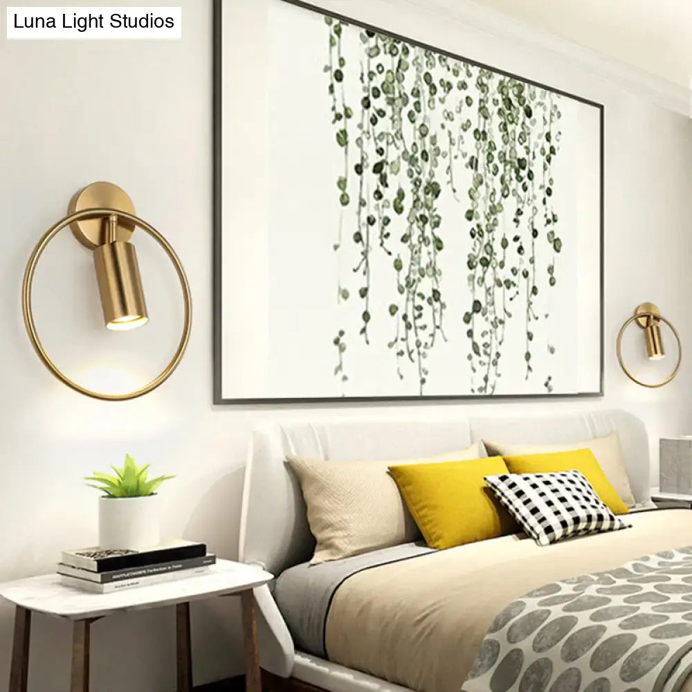 Postmodern gold-toned circular wall sconce with cylindrical lamp head and 16 inches fixture height for bedroom use