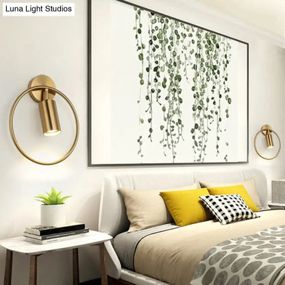 Postmodern gold-toned circular wall sconce with cylindrical lamp head and 16 inches fixture height for bedroom use