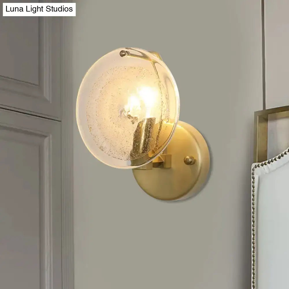 Postmodern gold metal wall sconce with a textured clear glass shade for bedroom lighting