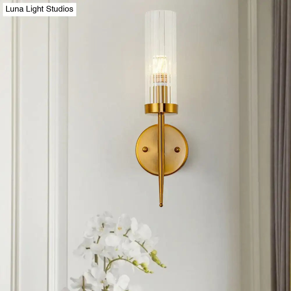 Postmodern gold wall sconce with clear ribbed glass cylindrical shade and slender metallic stem for stairway lighting
