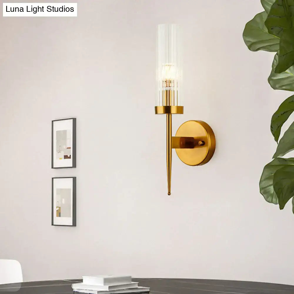 Postmodern gold ribbed glass wall sconce featuring a clear ribbed glass cylinder and slender metallic stem for stairway lighting