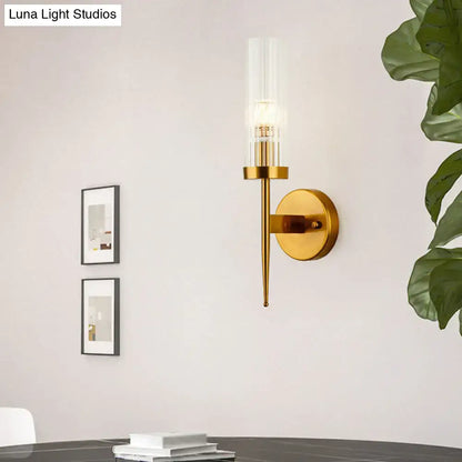 Postmodern gold ribbed glass wall sconce featuring a clear ribbed glass cylinder and slender metallic stem for stairway lighting