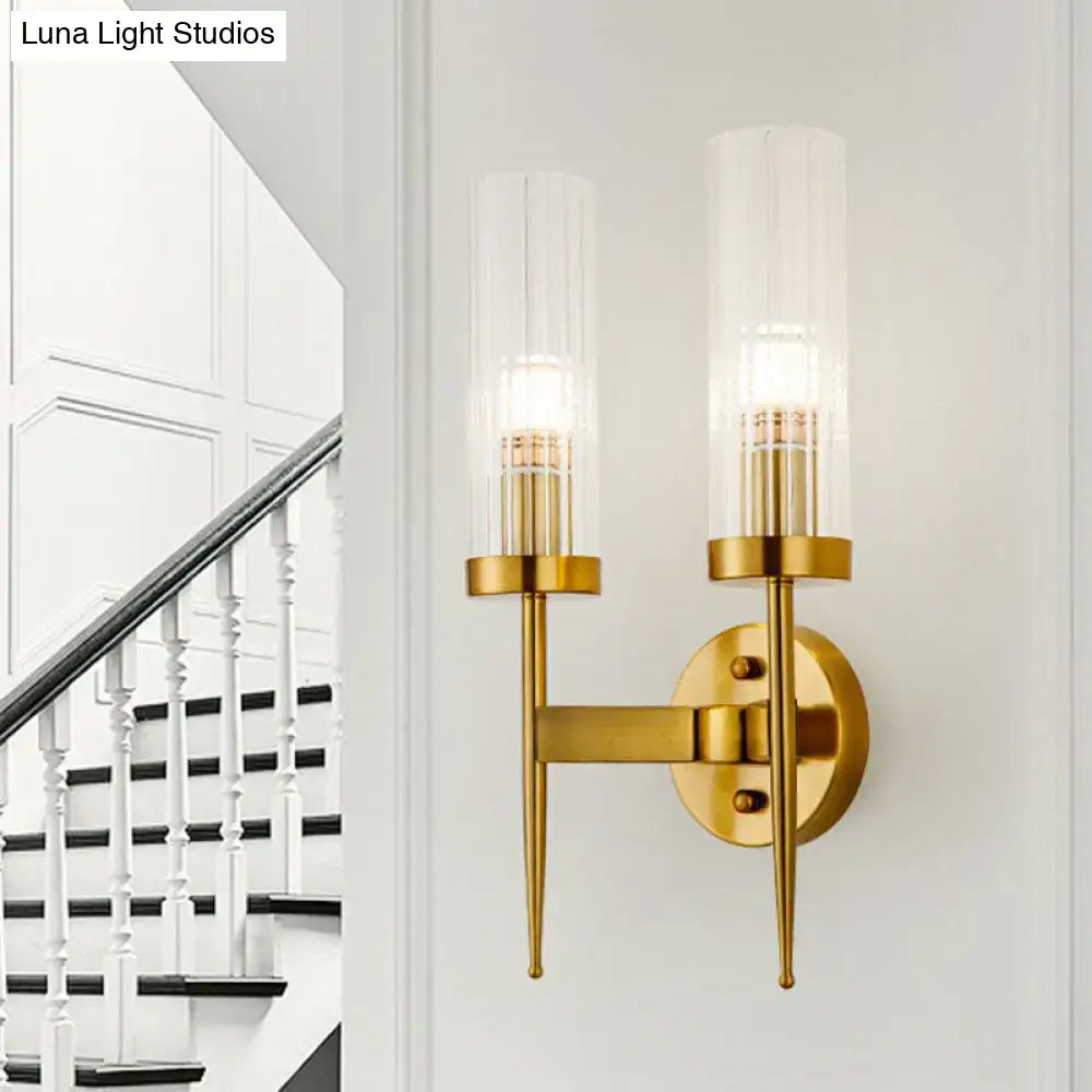 Postmodern gold-toned wall sconce with clear ribbed glass cylindrical shades and slender metallic arms for stairway lighting