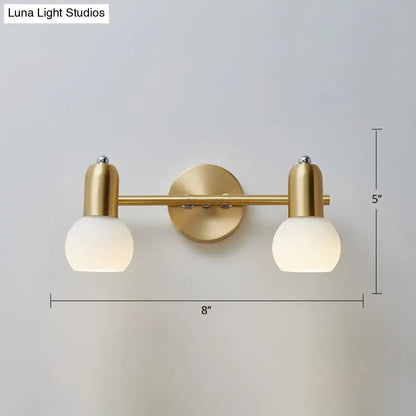 Gold-toned postmodern wall sconce with two dome milk glass shades and minimalist bar design for milk glass vanity light