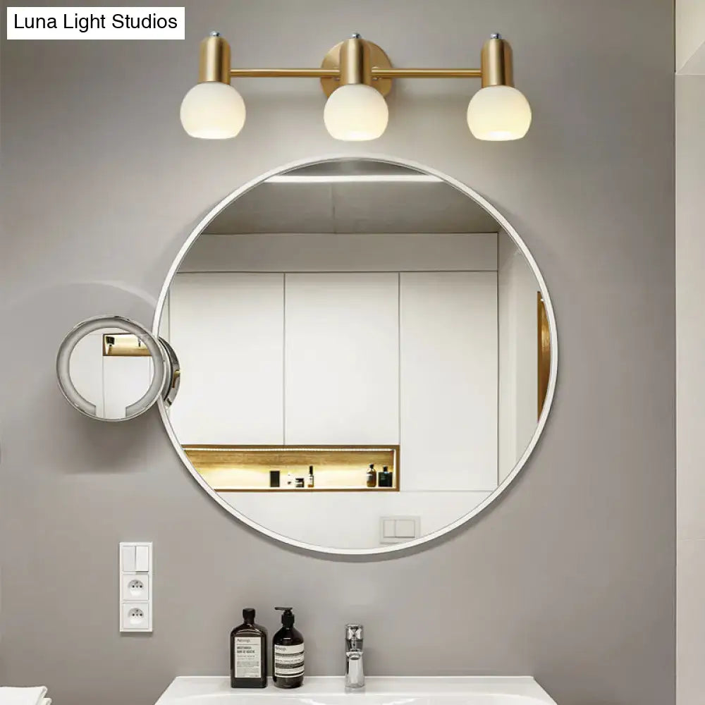 Round white-framed bathroom mirror with attached magnifying mirror and postmodern gold dome milk glass vanity light sconce