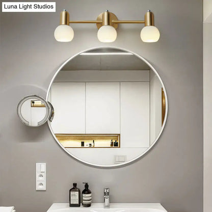 Round white-framed bathroom mirror with attached magnifying mirror and postmodern gold dome milk glass vanity light sconce