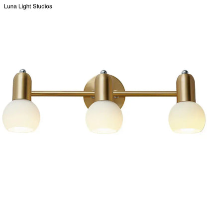 Postmodern gold swivel dome milk glass vanity light featuring three frosted glass globe bulbs for bathroom use