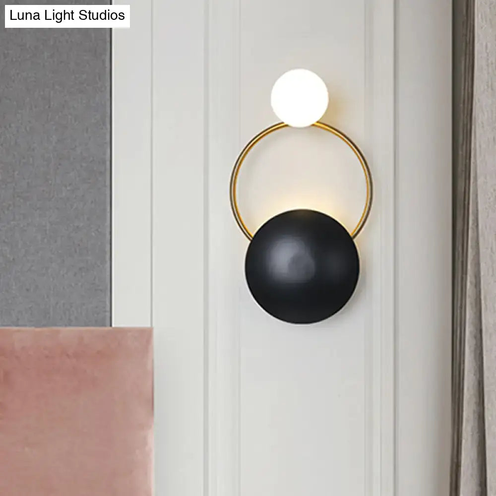 Postmodern orbital flush mount wall sconce with gold circular frame, illuminated white bulb, and matte black shade for bedroom
