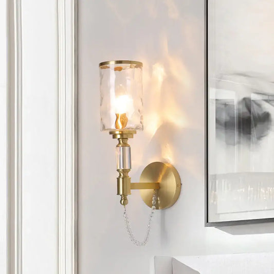 Postmodern water glass brass wall light featuring a textured glass shade and crystal accents for bedroom use