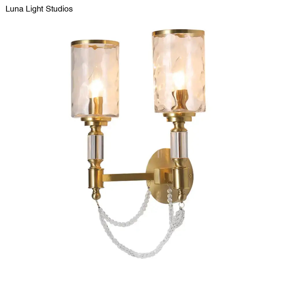 Postmodern water glass brass wall light featuring gold-finished sconce with two textured glass shades and crystal chain detail