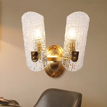 Gold-toned wall light with two clear textured prism glass shades featuring a subtle grid pattern for corridor use