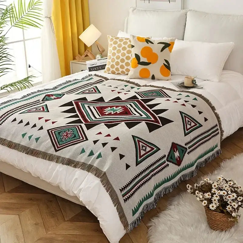 Cozy off-white woven ethnic tapestry sofa blanket with bold maroon teal and black geometric patterns and fringed edges