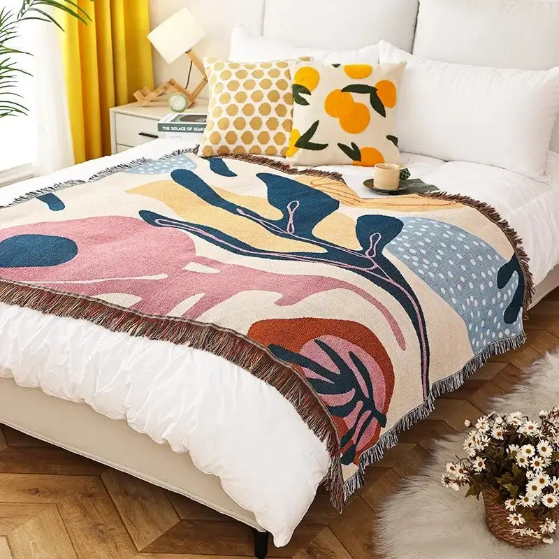 Cozy ethnic tapestry sofa blanket with abstract pastel and navy blue patterns and fringed edges for living rooms