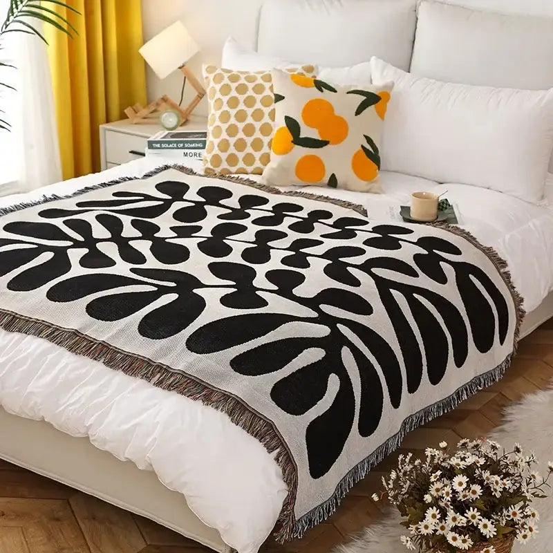 Black and white leaf-patterned ethnic tapestry sofa blanket with fringed edges for olive and pink living room decor