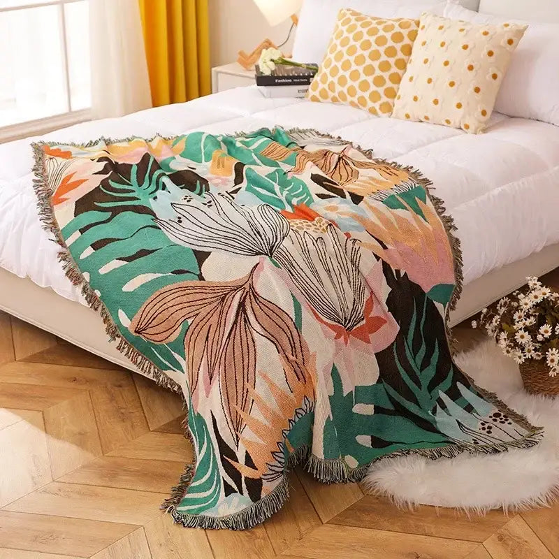 Vibrant ethnic tapestry sofa blanket with tropical leaf pattern in bold greens pinks and oranges on soft textured weave