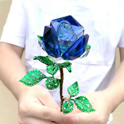 A vibrant blue crystal rose figurine with faceted petals and green enamel leaves on a metallic stem for living room decor