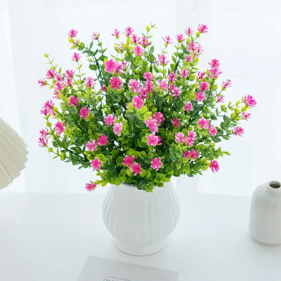 A vibrant pink decorbites artificial eucalyptus plant with lush green leaves in a white ceramic vase for decor