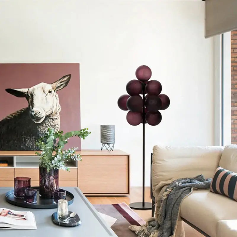 A modern floor lamp with deep burgundy glass spheres on a black metal stand in a decorbites grape chandelier design