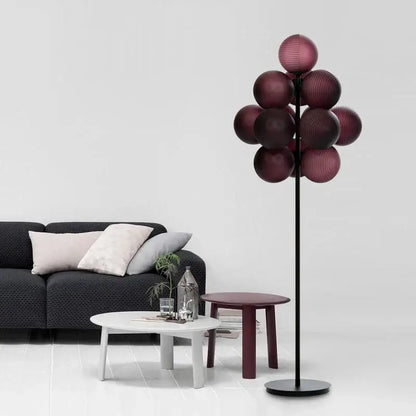 A modern floor lamp with a slender black stand and multiple deep burgundy glass shades in decorbites grape chandelier style