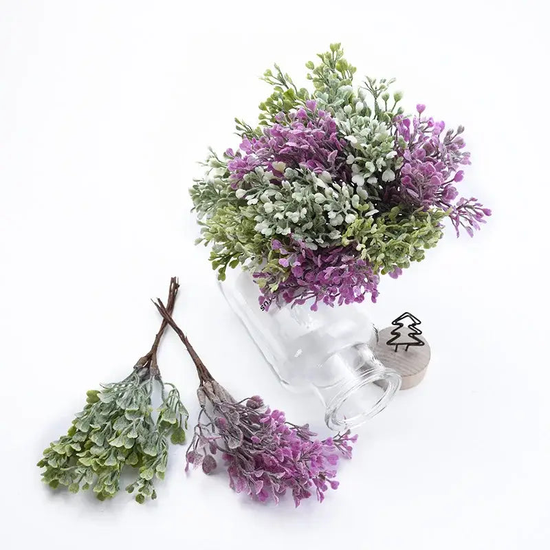 A decorbites artificial flower vase with a delicate purple and green artificial flower bouquet in a clear glass bottle