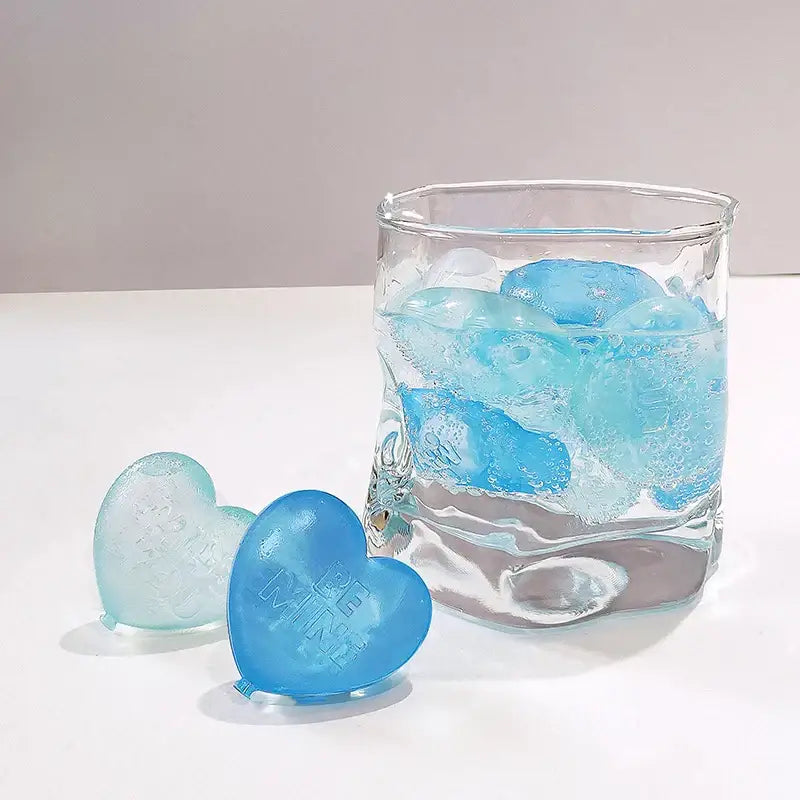 Blue heart-shaped ice cubes with embossed text made using a purple heart ice cube mold reusable kitchen tray