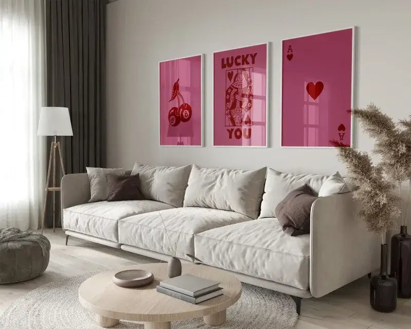 Three framed pink playing card wall art prints from decorbites™ 3-piece retro queen of hearts art set above beige sofa