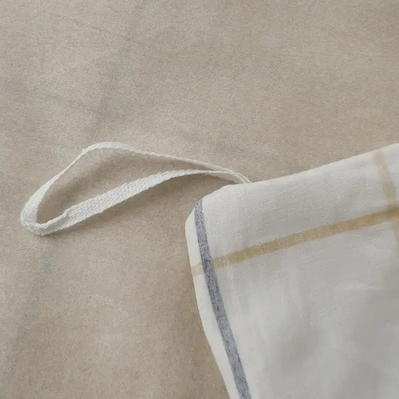 White fabric pillowcase with beige and gray stripes and woven cotton tie from geometric printed bed set