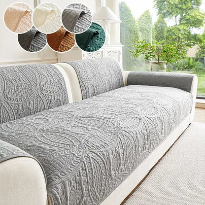 Gray quilted sofa cover with an intricate leaf pattern.