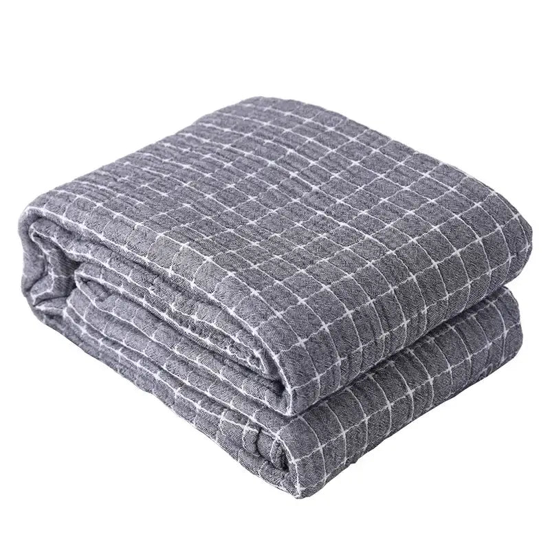 Gray quilted blanket with subtle white grid pattern made of decorbites cotton gauze for use as a sofa cover or throw