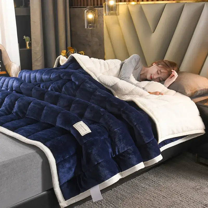 A plush navy blue and white quilted bed blanket with cozy coral fleece fabric for comfortable bedroom use