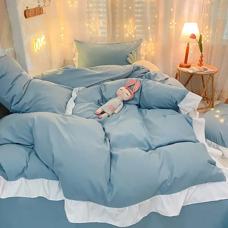Soft pastel blue quilted duvet cover set with white ruffle trim and plush bunny doll on bedroom bedding
