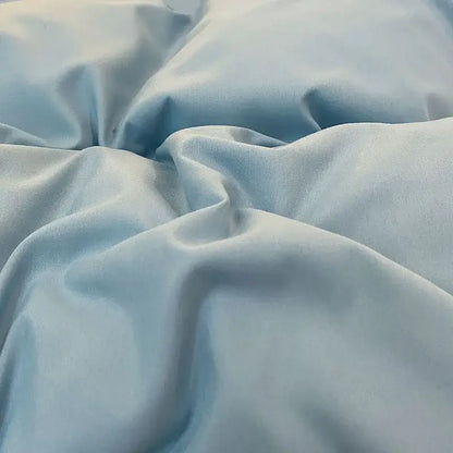 Quilted light blue and white ruffle duvet cover set featuring soft satin fabric with gentle folds and smooth reflective surface