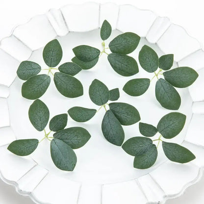 Dark green artificial roses with detailed veining 50pcs silk 5leaf artificial leaves on a white scalloped plate
