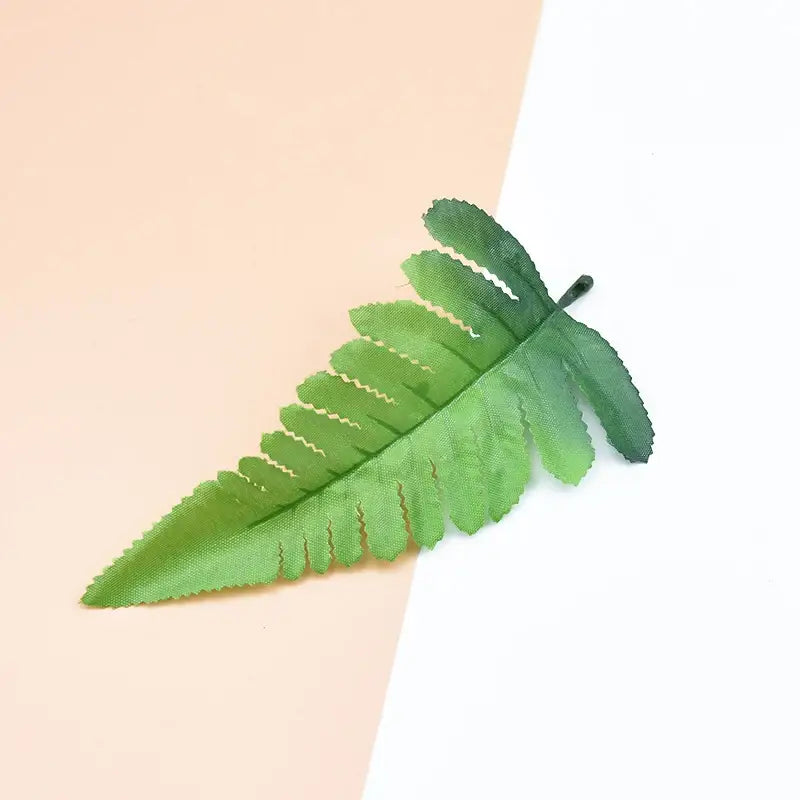 A vibrant green artificial fern leaf with textured fabric surfaces and serrated edges for decorbites decorative flowers artificial plants