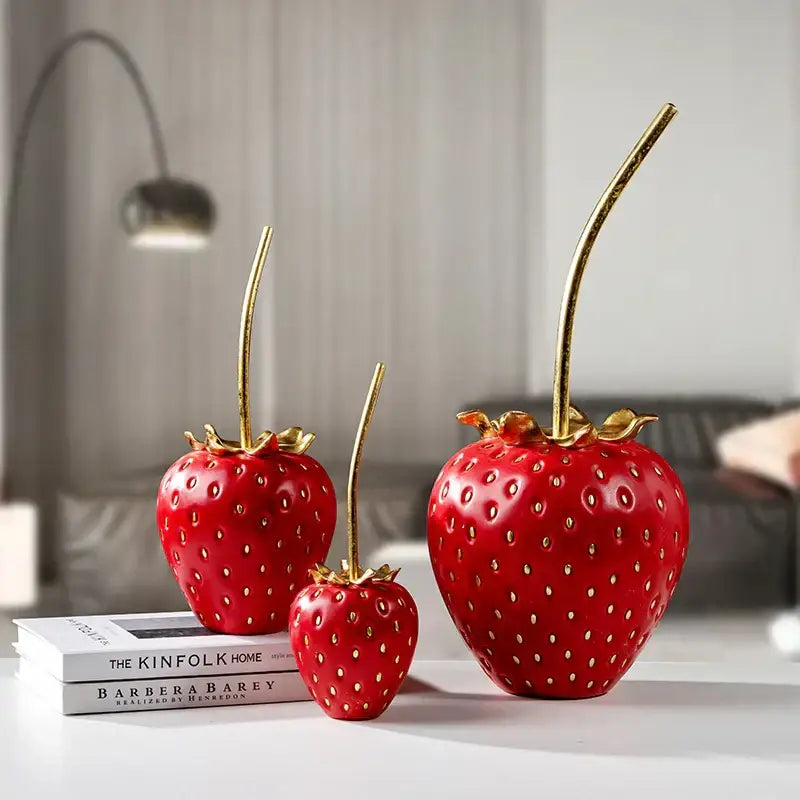 Three glossy red and gold strawberry figurines with leafy tops in polished resin for home decor and decorbites gold strawberry collection