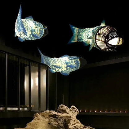 Red bamboo fish pendant light features three illuminated bamboo fish pendant lanterns with detailed scale patterns