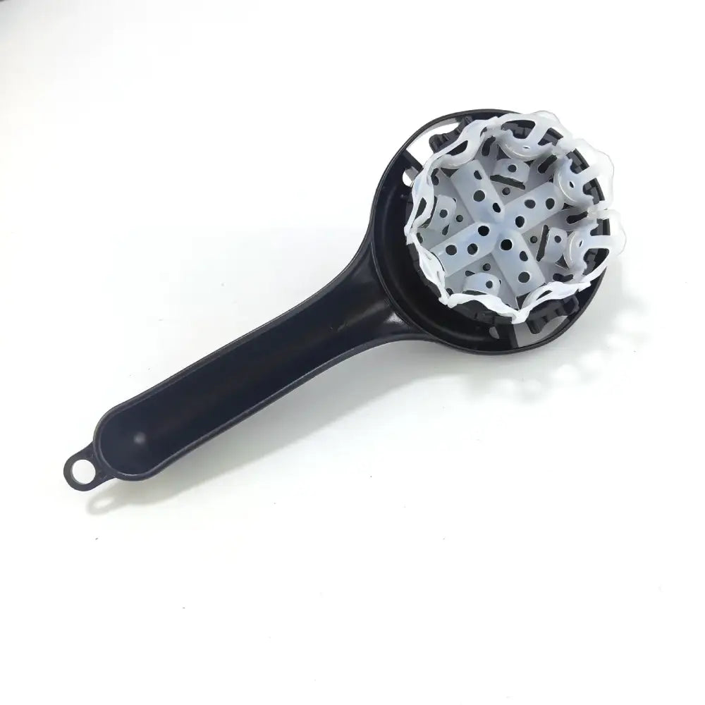 Black plastic hand-held fruit and vegetable juicer with white cross-shaped grinder used as espresso coffee machine cleaning tool