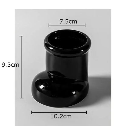 Black glossy ceramic vase with flared rim and rounded base shown as part of red ceramic boot desk organizer box for office use