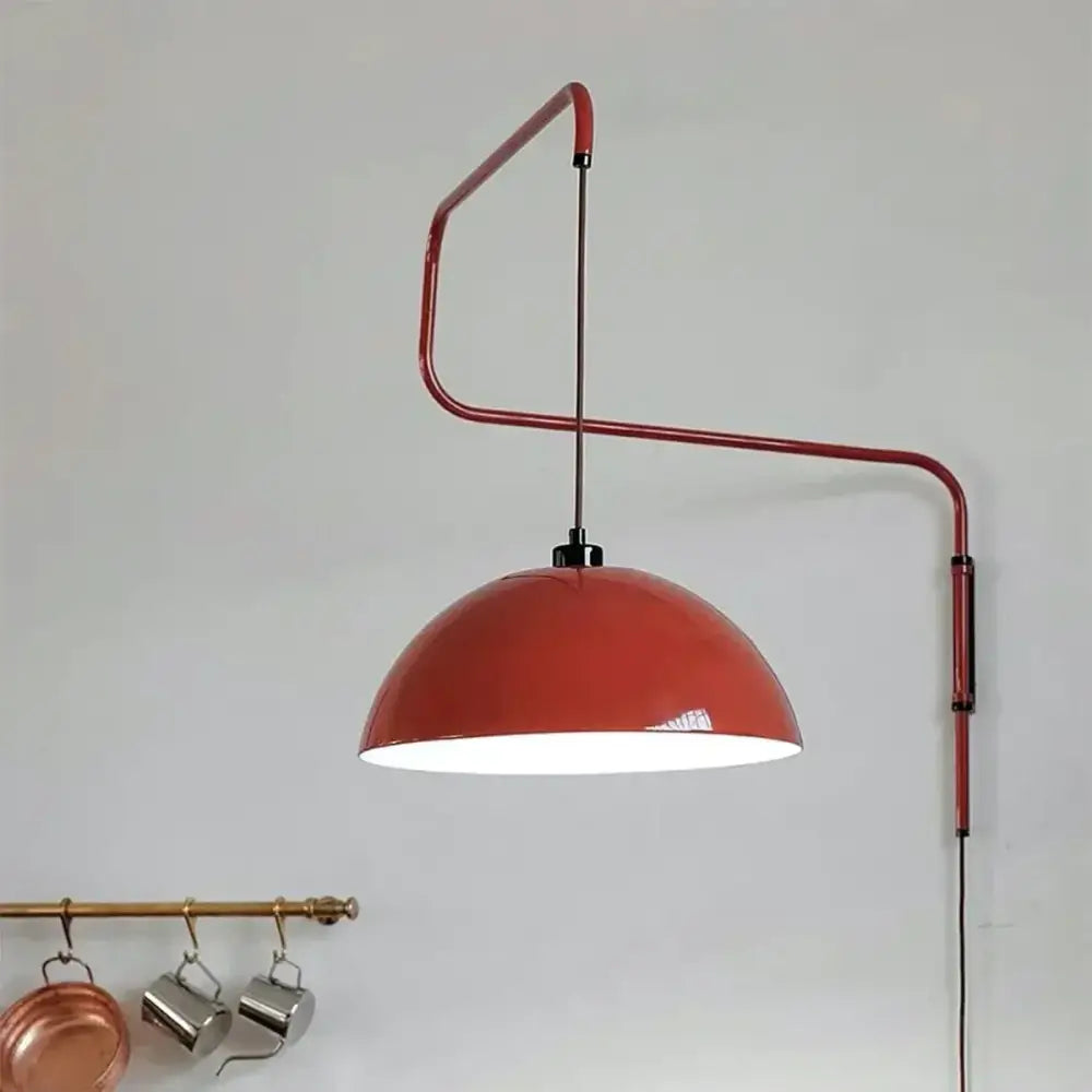 Red enamel dome adjustable pendant light with curved metal arm designed for kitchen island lighting