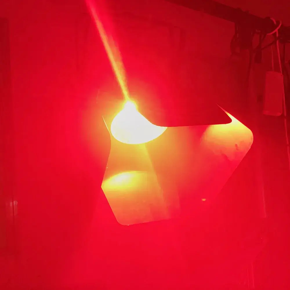 A glowing red led par cob stage light with black barn doors and warm yellow illumination for living room use