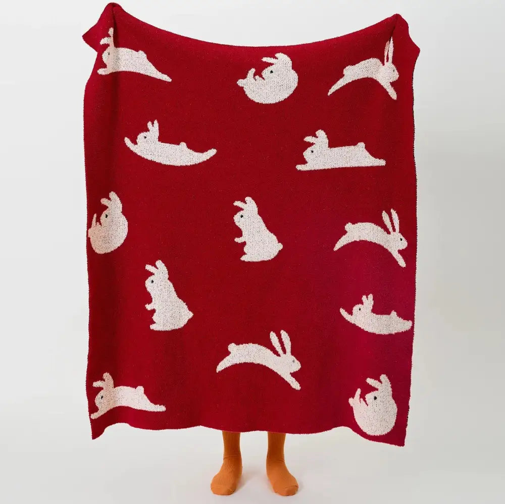 A cozy red knitted throw blanket with decorbites lively rabbit pattern featuring white rabbits for bedroom decor