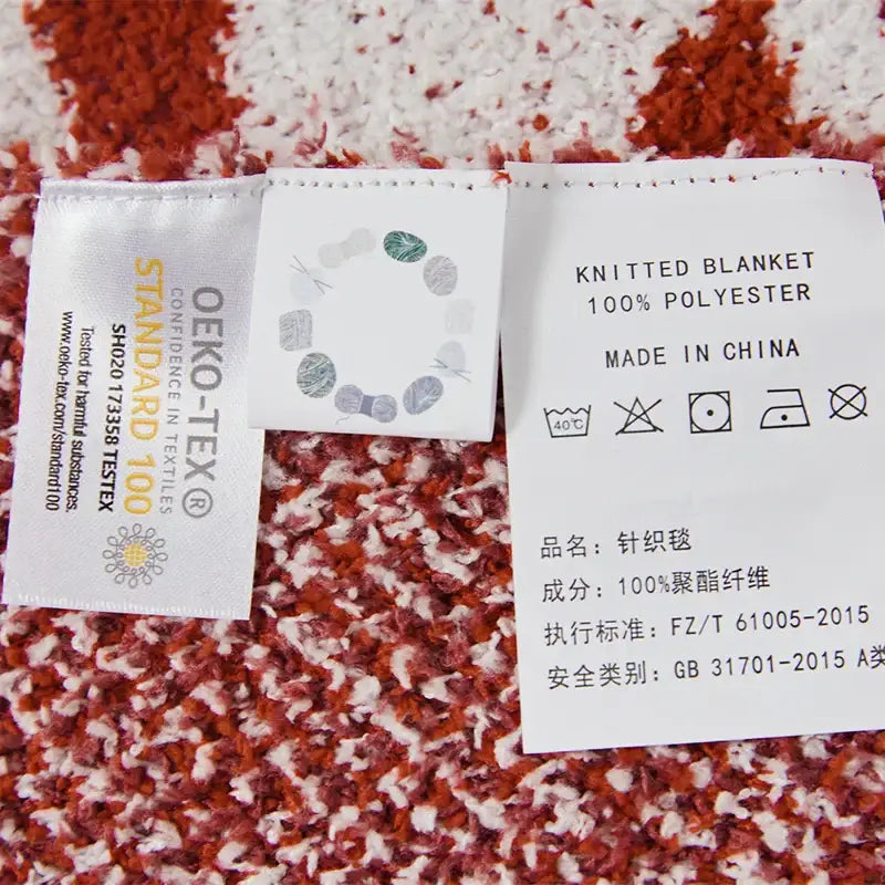 Back side of a red and white dragon zodiac decorbites knitted blanket with white and silver woven care labels