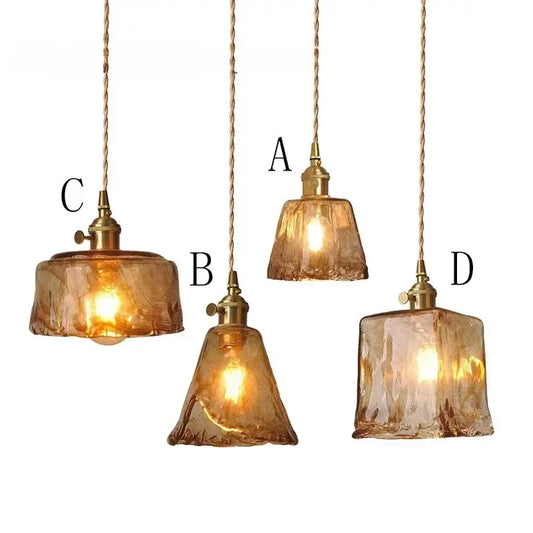 Four amber glass pendant lights with brass fixtures and twisted cords ideal for dining room lighting