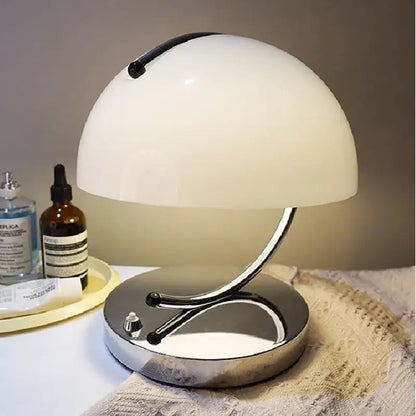 A sleek white dome-shaped decorbites glass table lamp with a chrome base and curved stem for stylish bedroom use